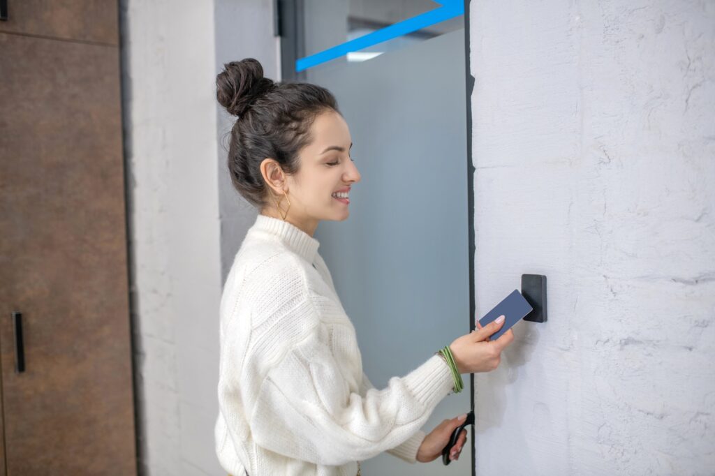 Young woman holding access card to unclock the door, smiling